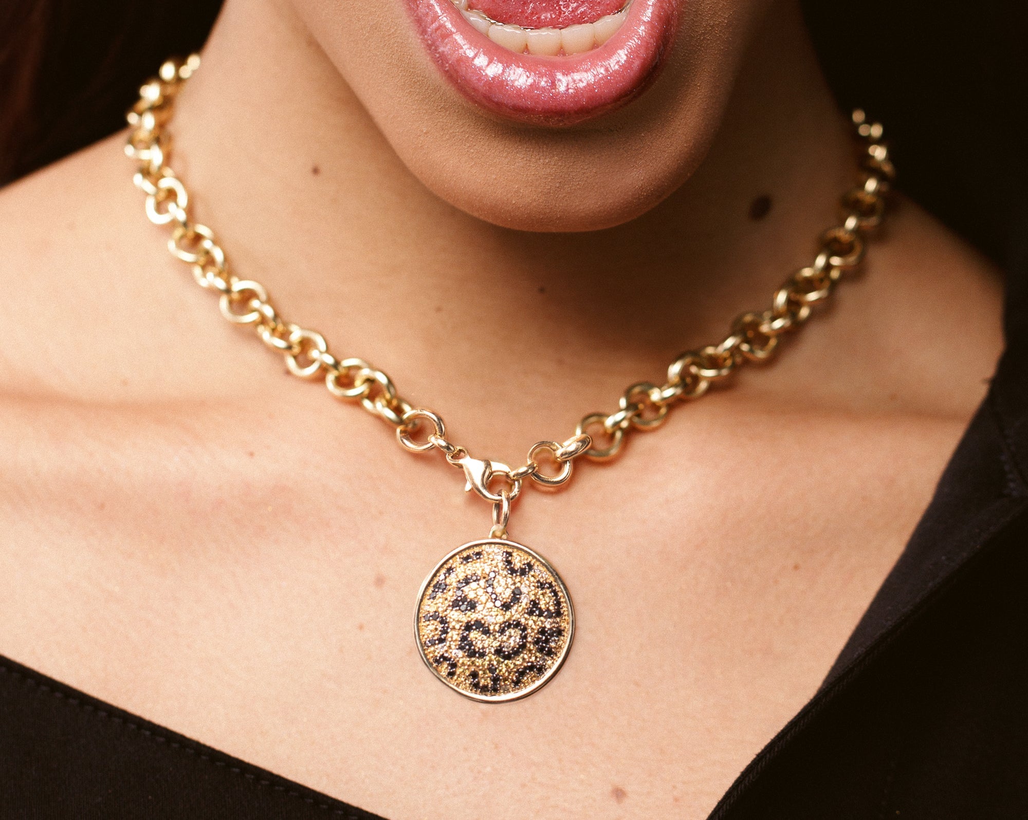 gemstone and gold leopard pendant on large gold chain link necklace worn on model's neck