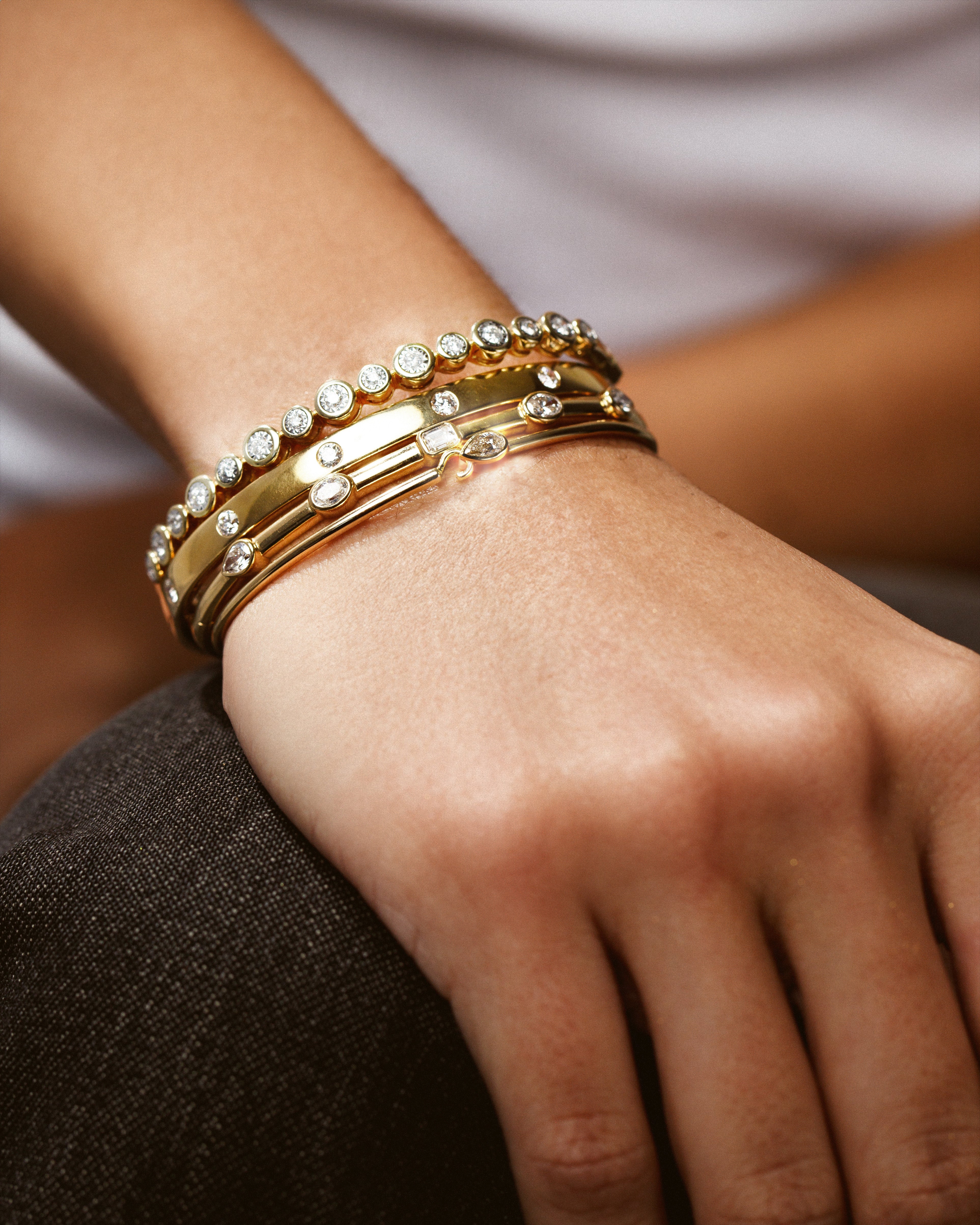 gold and diamond bracelets stacked on wrist