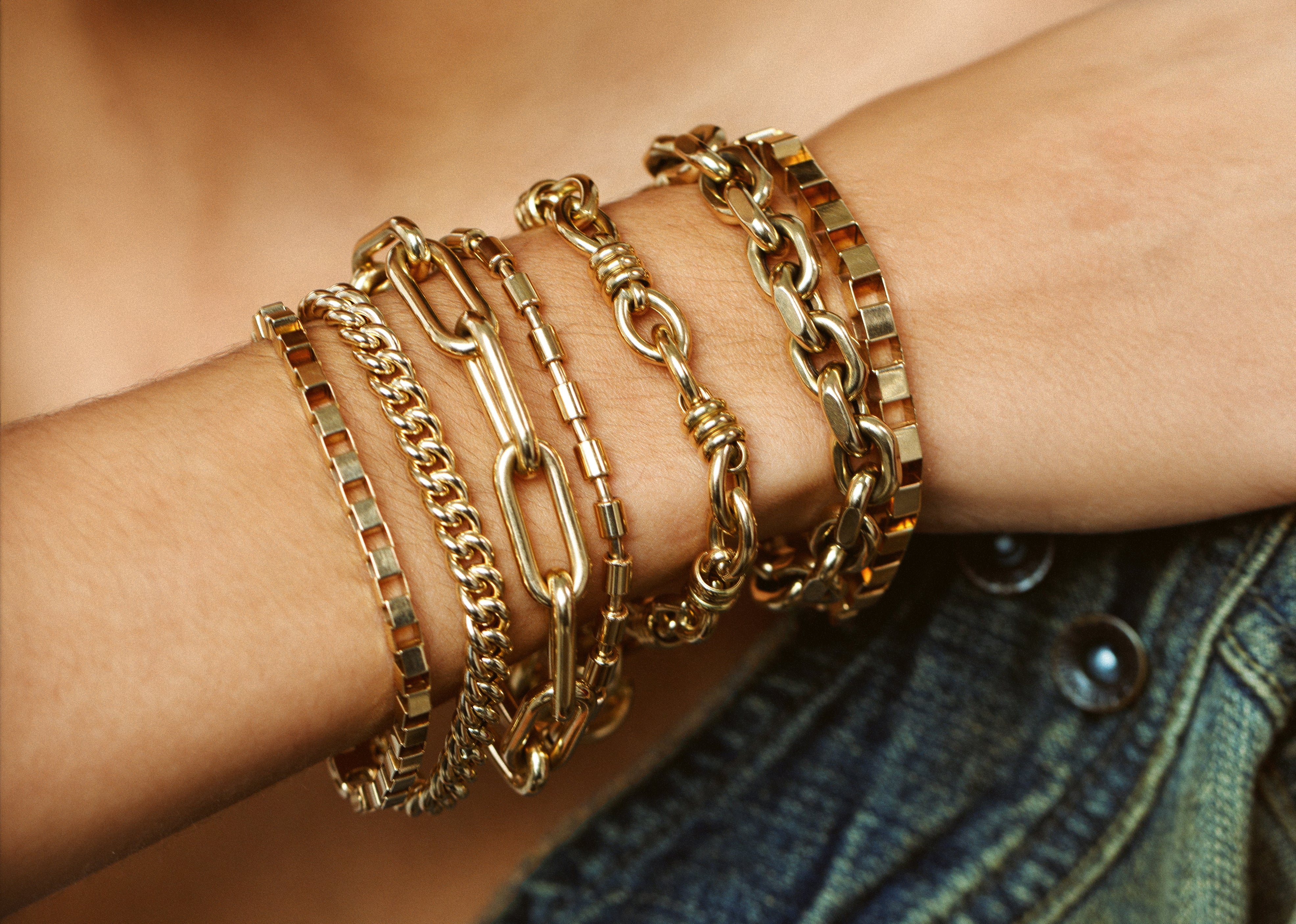 gold chain bracelets with different links stacked on wrist