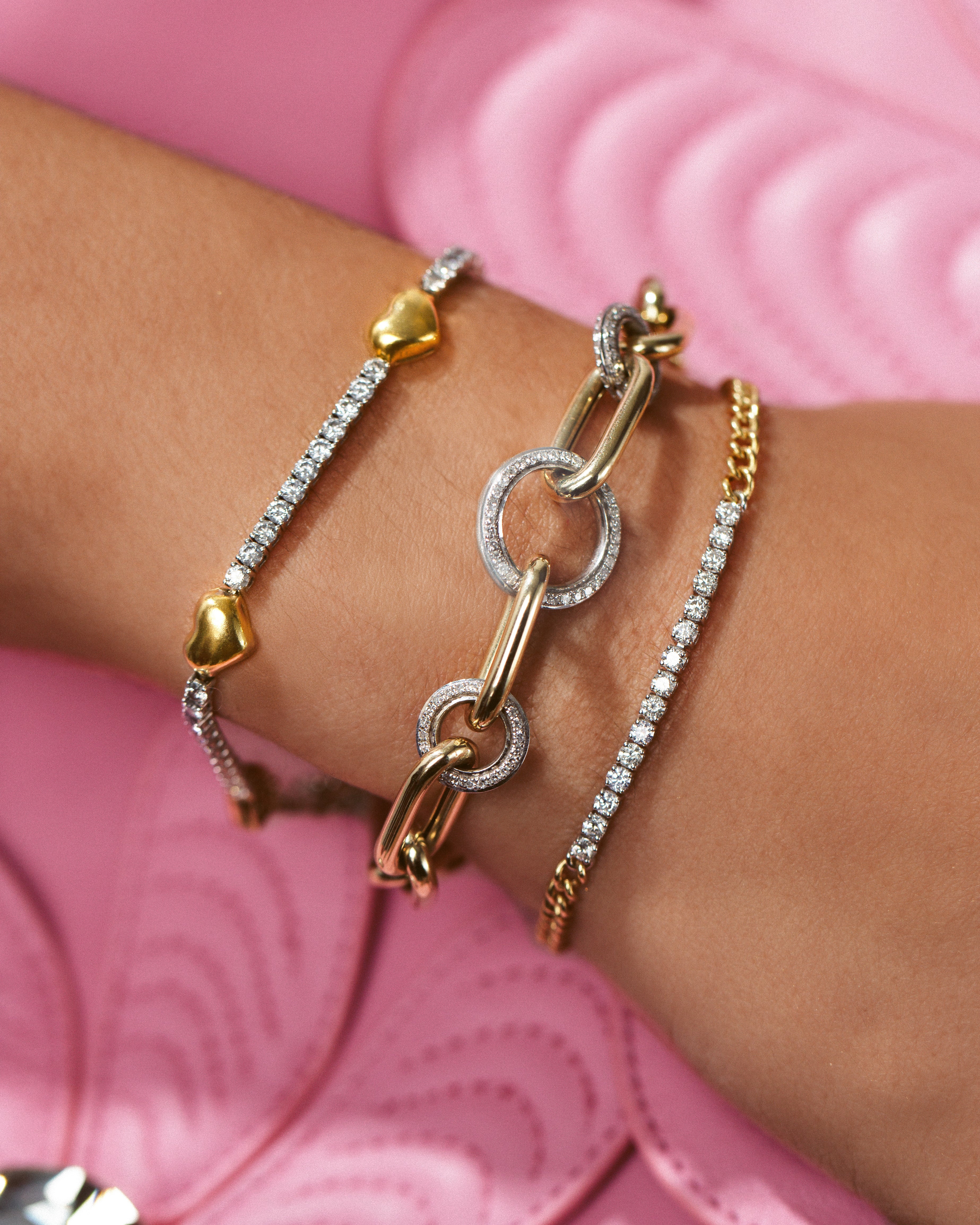 three gold and diamond tennis bracelet designs shown on wrist