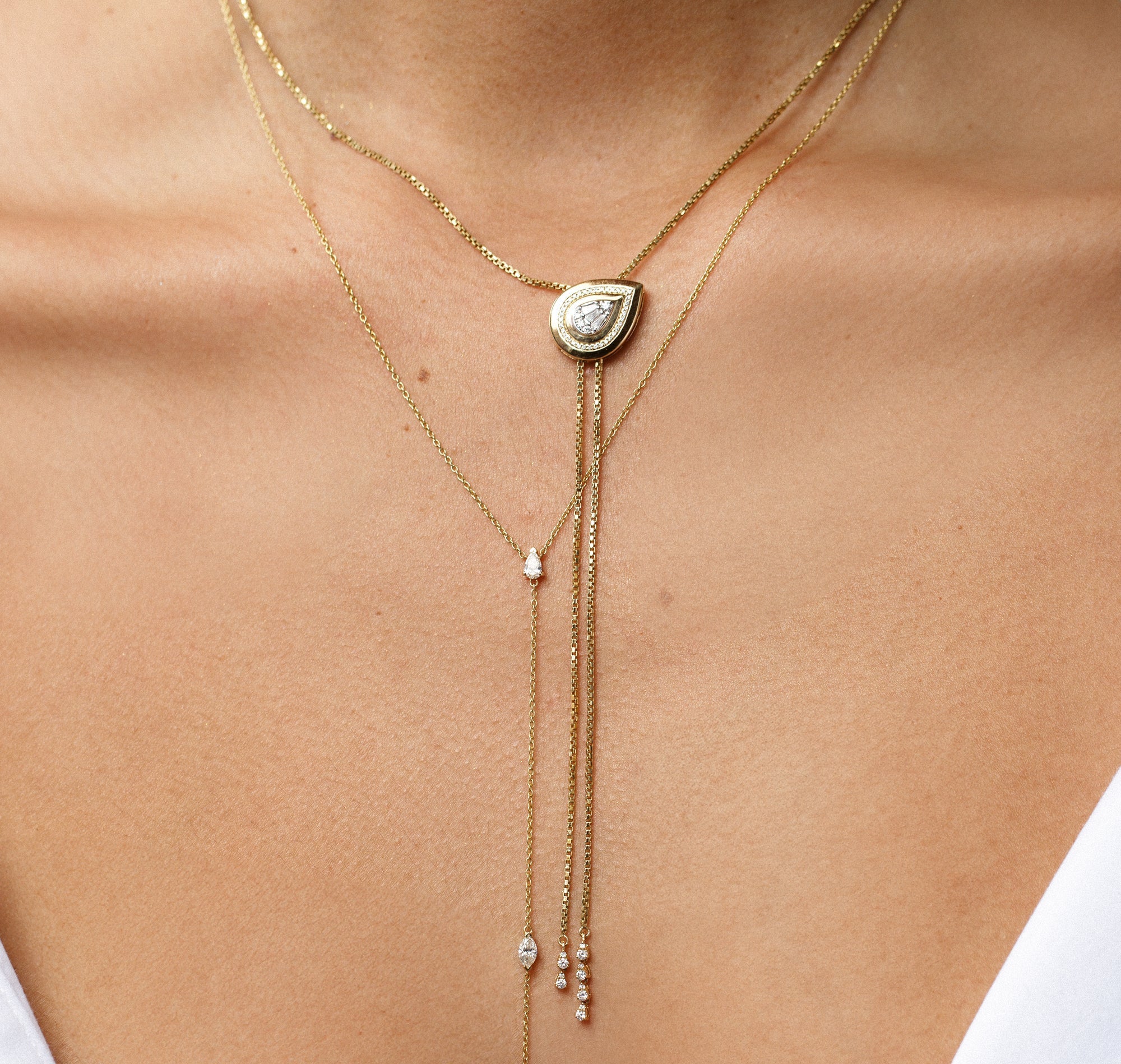 two gold and diamond lariat necklaces layered on neck