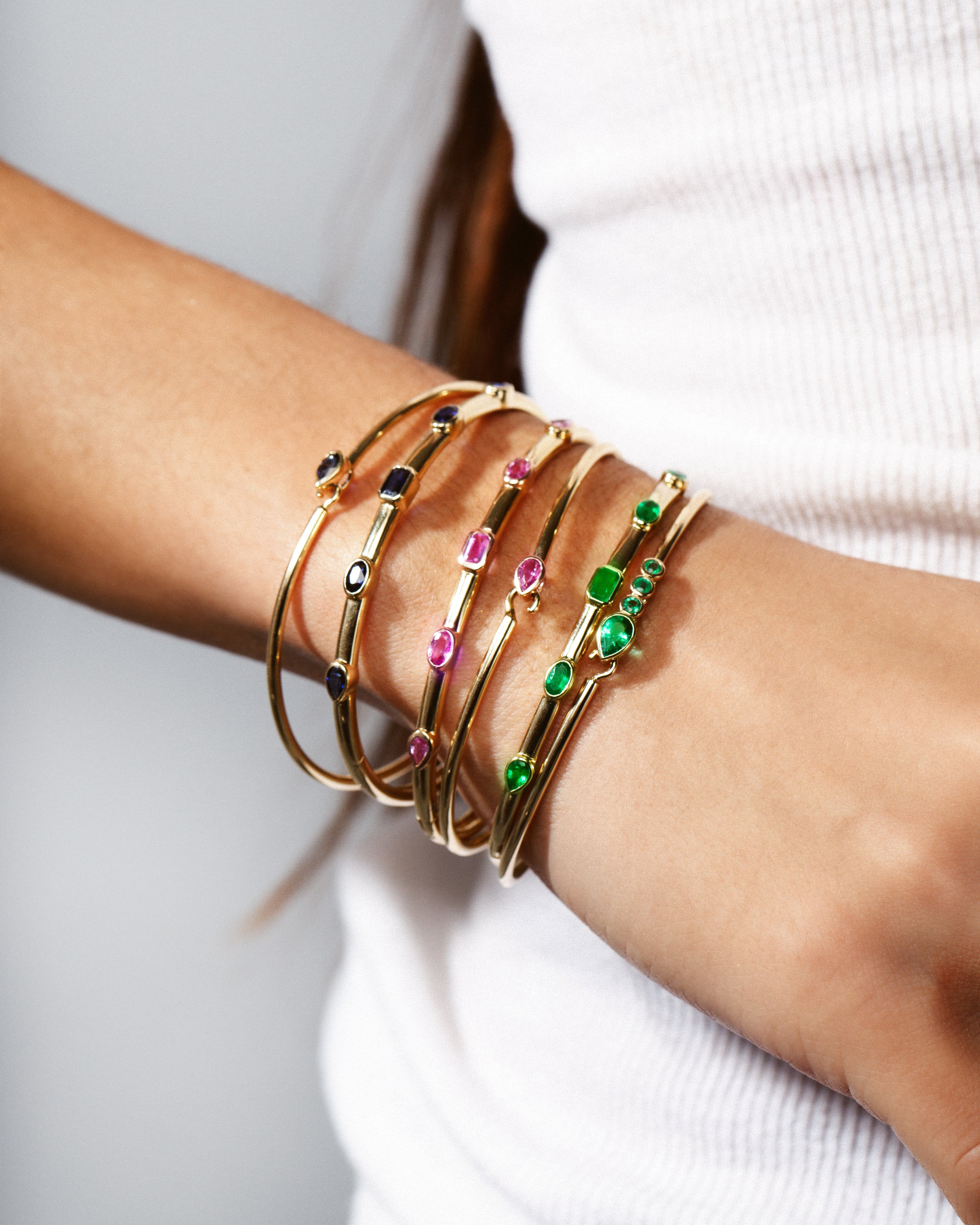 gold bangles and gold cuffs with gemstones stacked on wrist